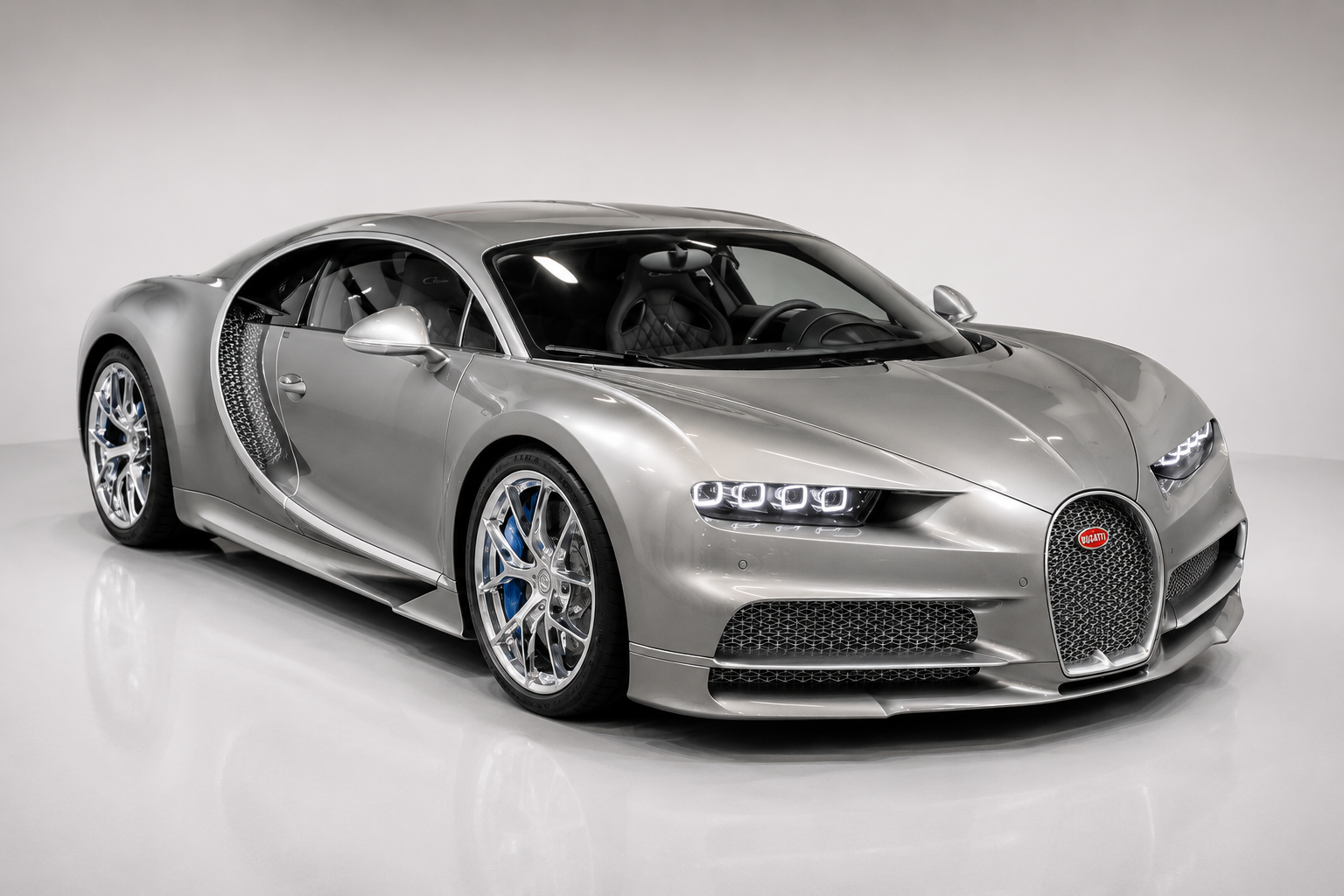 Silver Bugatti Chiron hypercar in a studio setting, front three-quarter view showing the signature horseshoe grille, quad LED headlamps, distinctive C-shaped side profile, polished multi-spoke wheels and the low-slung hypercar proportions.