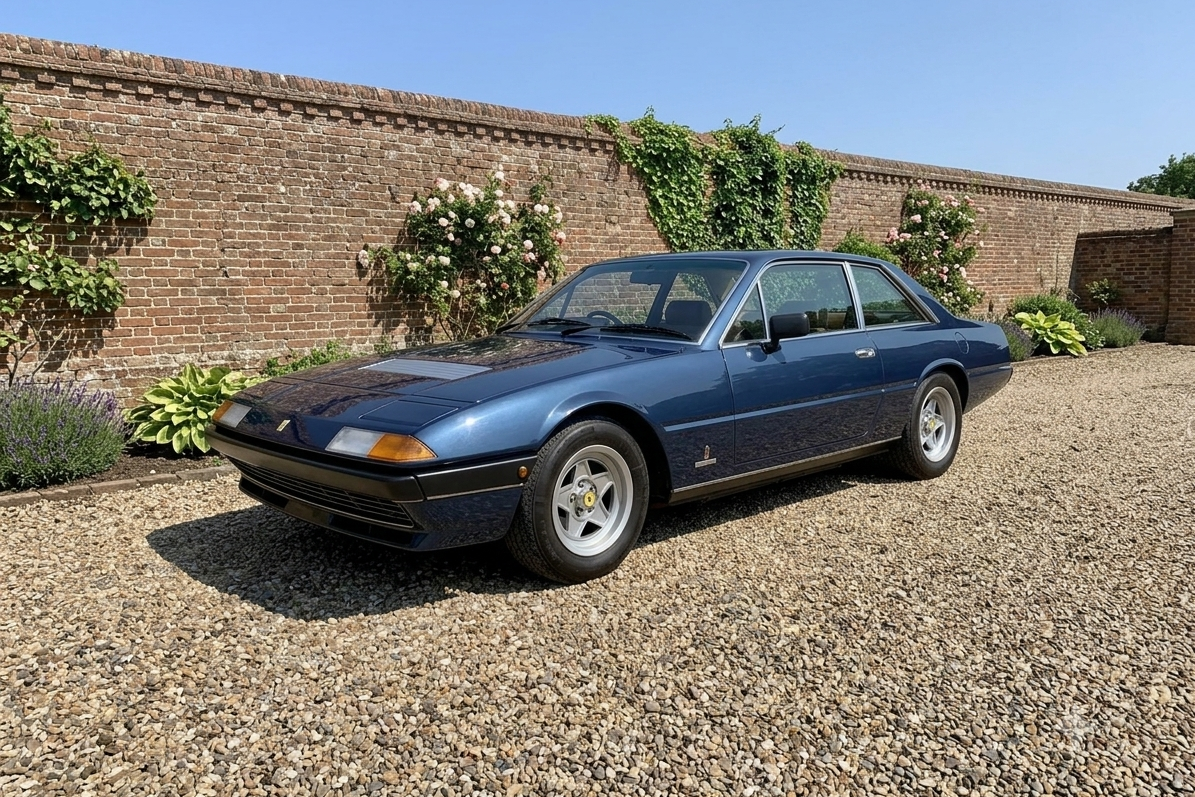 Ferrari 400, front three-quarter view — Pininfarina-designed 1976–1985 front-engined V12 2+2 grand tourer in dark metallic blue, five-spoke alloy wheels and retractable headlamps shown closed, set against a walled garden backdrop.
