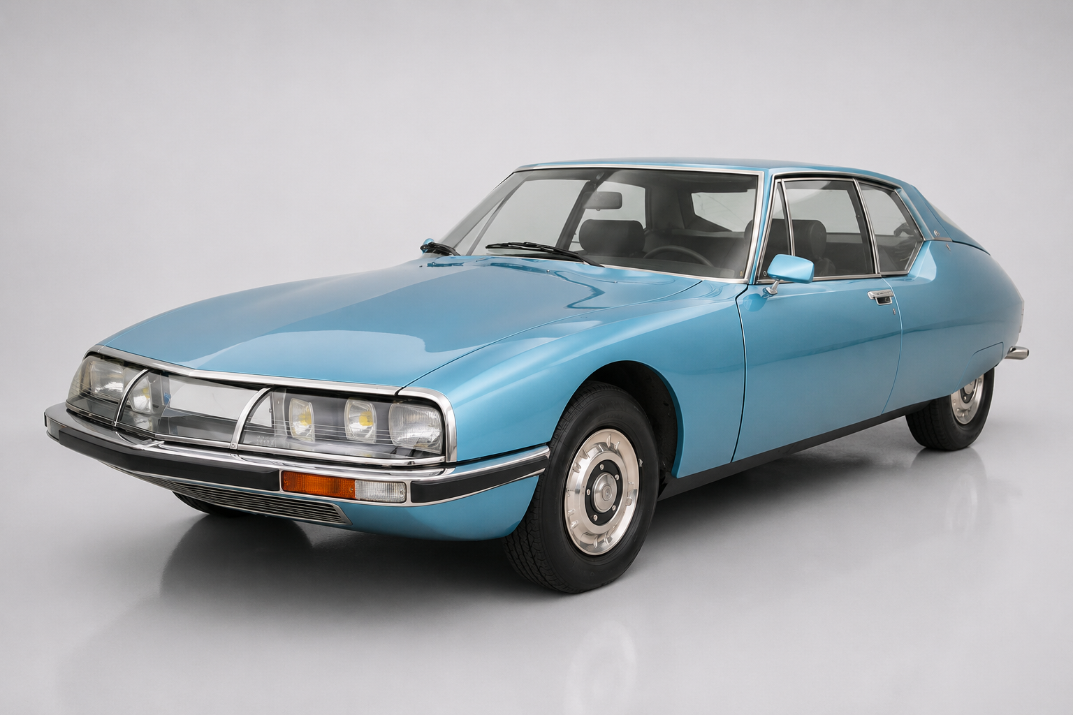 Light blue Citroën SM coupé, front three-quarter studio view, showing the glass-covered six-lamp nose panel, fastback roofline and flush wheel covers.