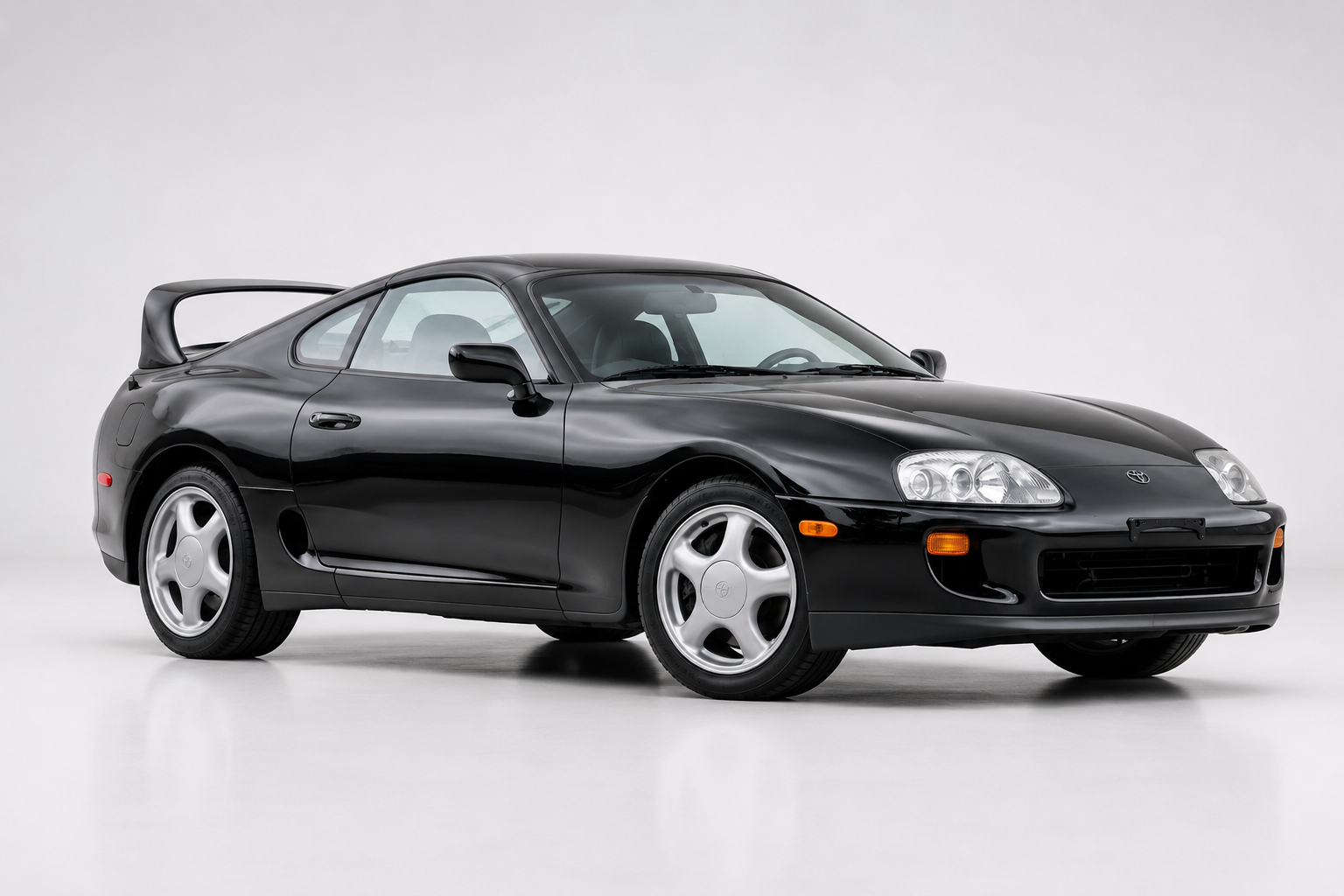 Black Toyota Supra A80 with rear wing, front three-quarter view
