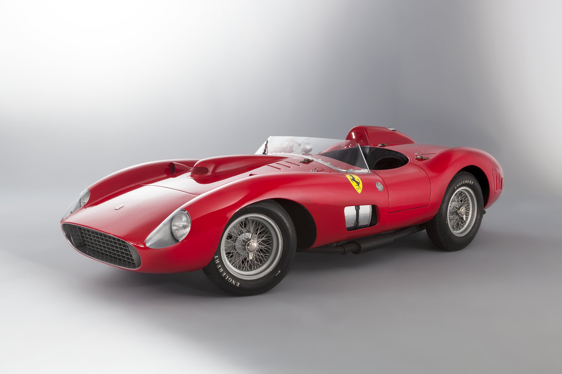 Ferrari 335 Sport Scaglietti, chassis 0674, in red, front three-quarter studio view on a pale grey backdrop, showing the Scaglietti barchetta bodywork in its original front-end configuration, aero screen and driver's headrest fairing, right-hand drive cockpit, Borrani wire wheels on Englebert tyres and the Scuderia Ferrari shield on the flank.