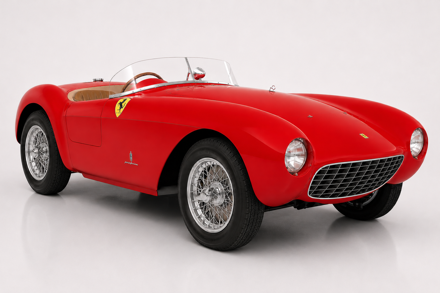 Red Ferrari 500 Mondial spyder photographed in a studio, front three-quarter view showing the oval mesh grille, faired-in headlamps, low windscreen, yellow Cavallino Rampante shield on the front wing and centre-lock wire wheels.