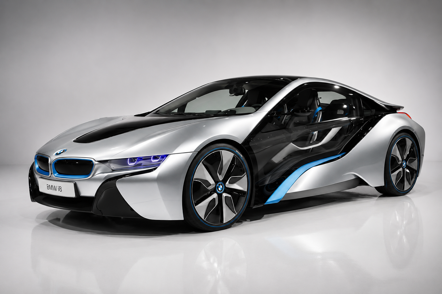 Silver and black BMW i8 plug-in hybrid sports car in a studio setting, front three-quarter view showing the blue-accented kidney grille, laser-style headlamps, butterfly doors, aerodynamic cut-outs and large turbine-style alloy wheels.
