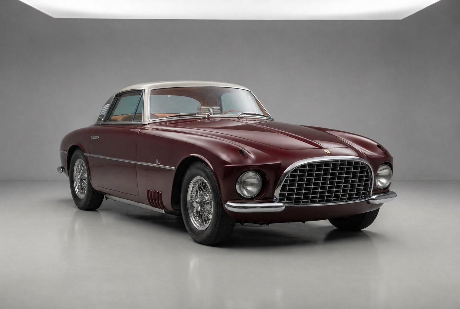 Ferrari 375 America Coupe by Vignale in burgundy with a silver-grey roof, front three-quarter studio view, showing the wide chrome egg-crate grille, headlamps recessed into nacelles in the front wings, chromed louvres behind the front wheel and aft of the side windows, Borrani wire wheels and a beige leather interior.