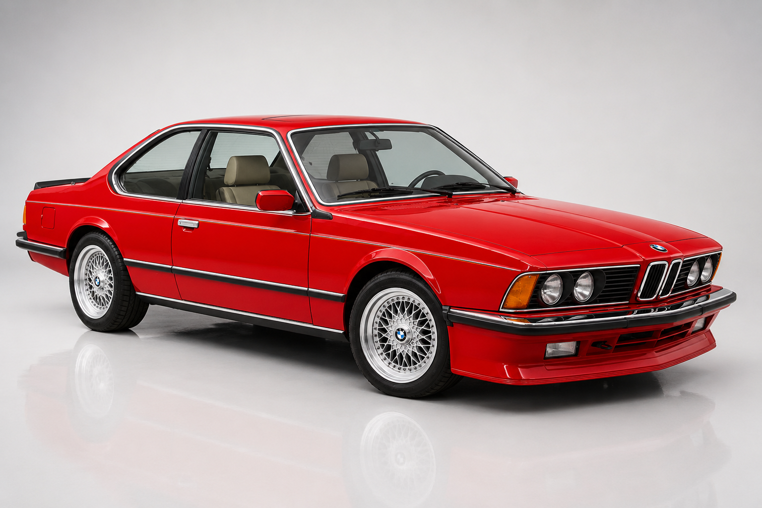 Red BMW M635CSi (E24) coupe, front three-quarter studio view showing the sharknose front, quad round headlamps behind glass, chrome kidney grille, black bumper trim and BBS-style cross-spoke alloy wheels on a light backdrop with a soft reflection.
