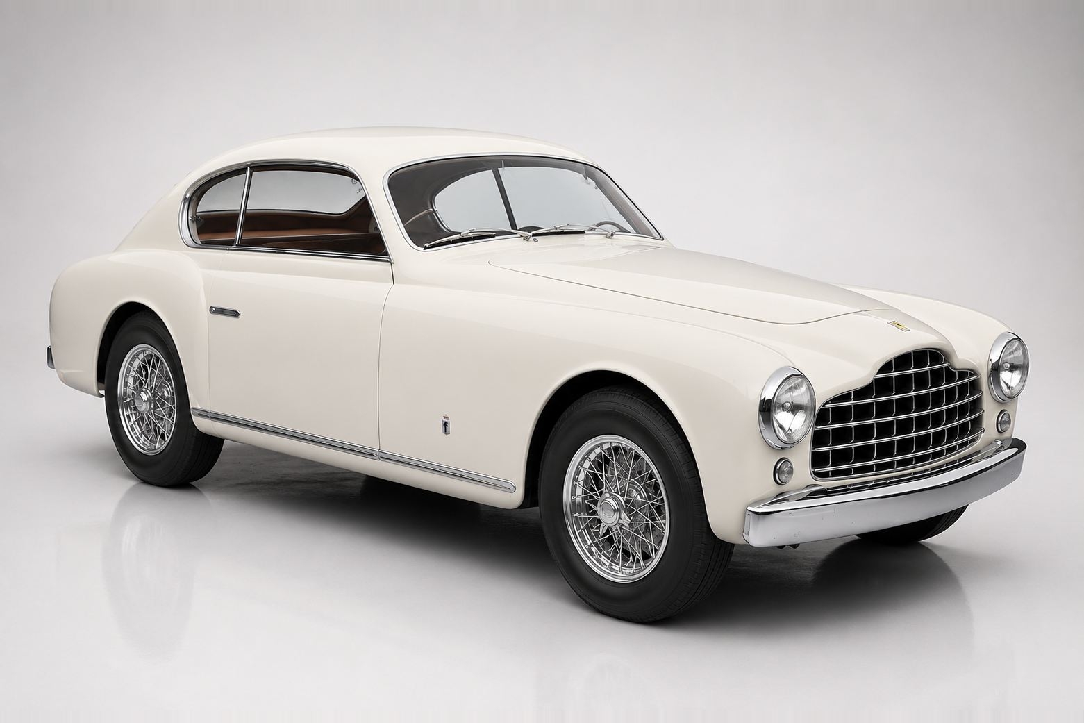 Cream Ferrari 195 Inter coupé photographed in a studio, front three-quarter view showing the small oval grille with vertical bars, faired-in headlamps, low bonnet, curved fender line and centre-lock wire wheels with chrome spinners.