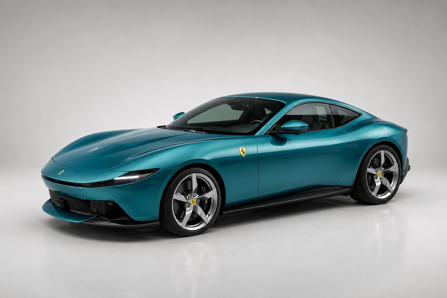 Teal-green Ferrari Amalfi coupé photographed in a studio, front three-quarter view showing the smooth body-coloured nose, slim LED headlamps with connecting light bar, yellow Cavallino Rampante shield on the front wing and multi-spoke alloy wheels.