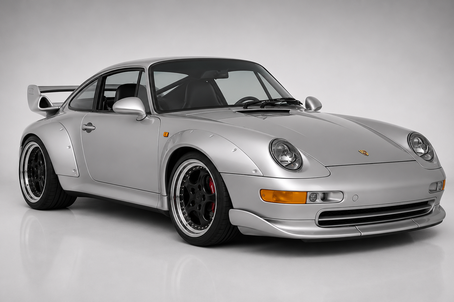 Silver Porsche 911 GT2 (993) in a studio, front three-quarter view showing riveted plastic wide-body arches, fixed biplane rear wing and centre-lock black modular wheels.