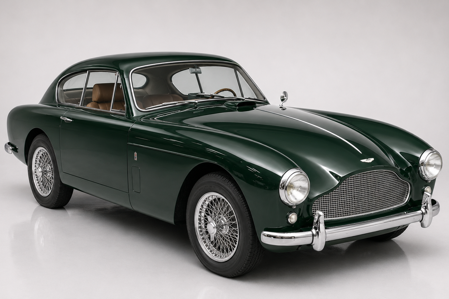 Dark green Aston Martin DB Mark III fixed-head coupe in a bright studio, front three-quarter view showing the DB3S-derived scalloped grille that would carry through to the DB4, DB5 and DB6, round headlamps, chrome bumpers, chrome wire wheels and a tan leather interior.