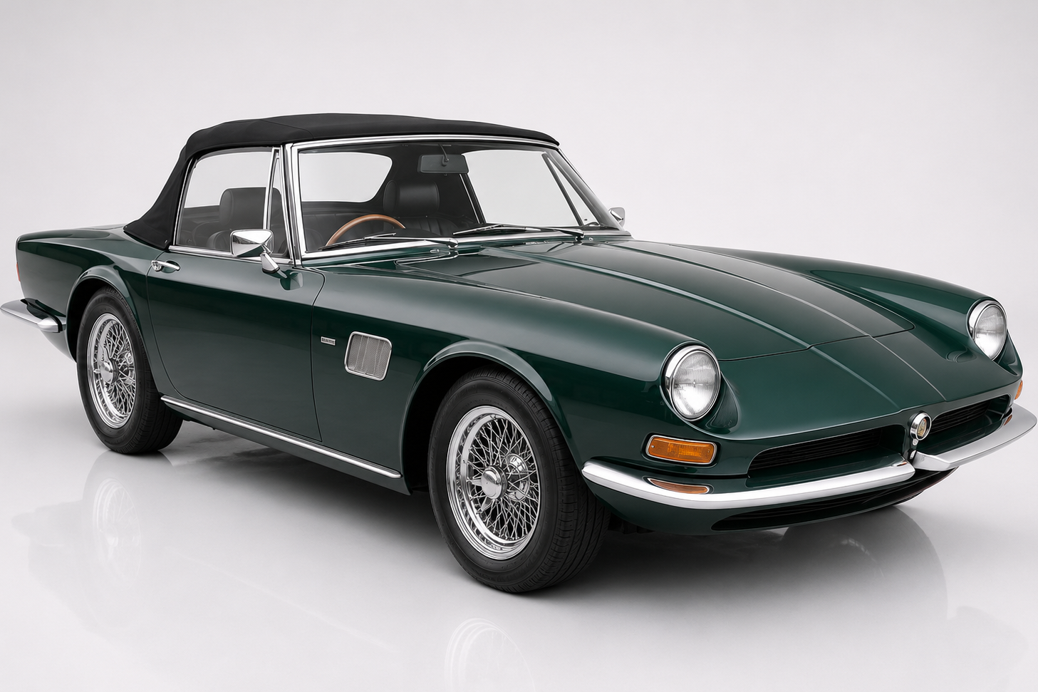Dark green AC 428 Frua drophead coupé with black soft-top raised, photographed in a studio setting — front three-quarter view showing the Frua-designed Italianate steel body, delicate chrome bumper and wire wheels over a Cobra 427 MkIII ladder chassis with Ford FE big-block V8 underneath.