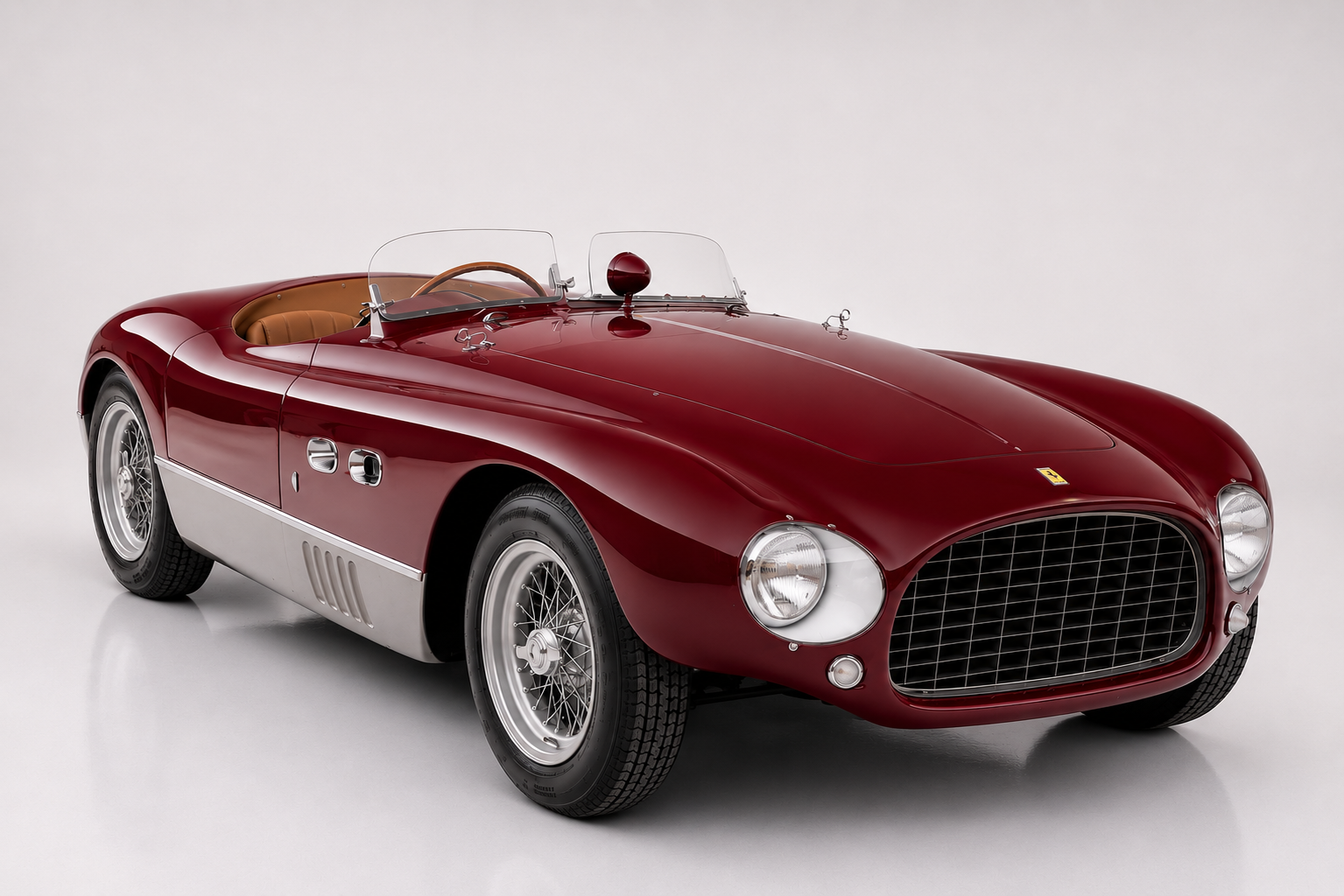 Dark red Ferrari 625 TF spyder with a bare aluminium lower body panel photographed in a studio, front three-quarter view showing the oval mesh grille, low racing windscreen, chrome bonnet-hinge fairings and centre-lock wire wheels.