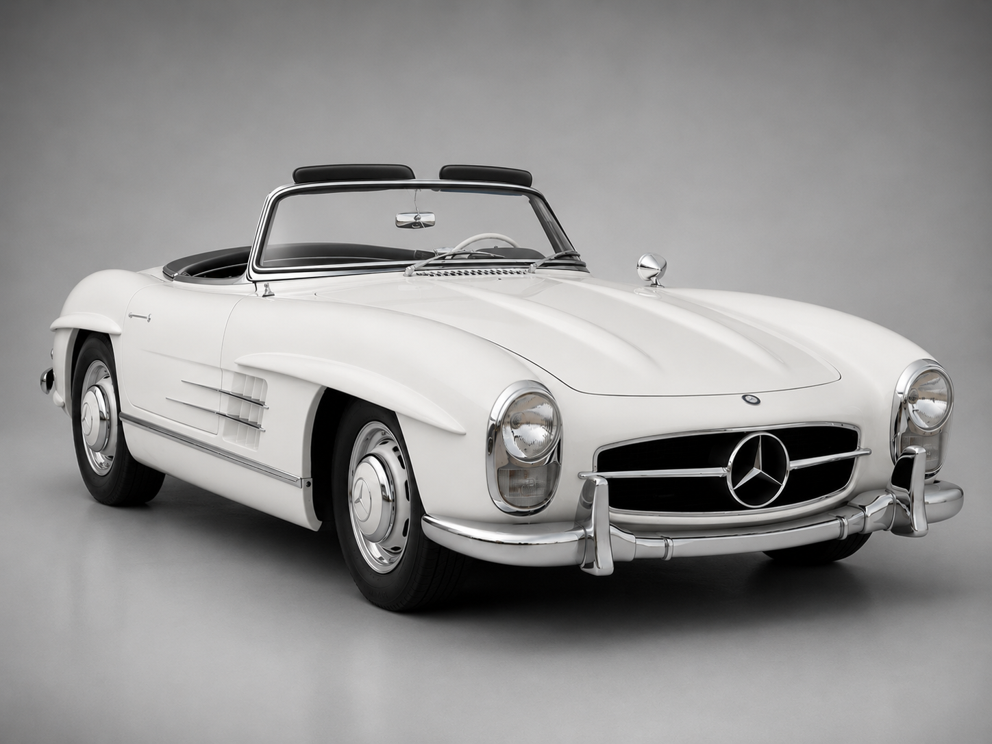 White Mercedes-Benz 300 SL Roadster with black soft top, chrome brightwork and wheel covers, photographed against a neutral grey studio backdrop.