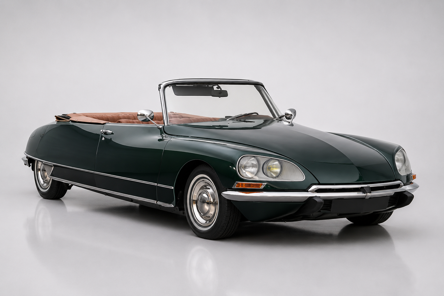 Dark green Citroën DS Décapotable (Chapron convertible), front three-quarter studio view with the top down, showing the faired-in directional headlamps, single-spoke wheel and aerodynamic bodywork.