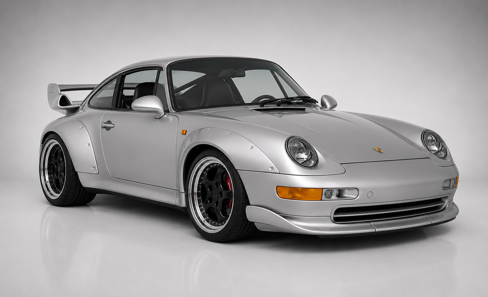 Silver Porsche 911 GT2 (993) in a studio, front three-quarter view showing riveted plastic wide-body arches, fixed biplane rear wing and centre-lock black modular wheels.