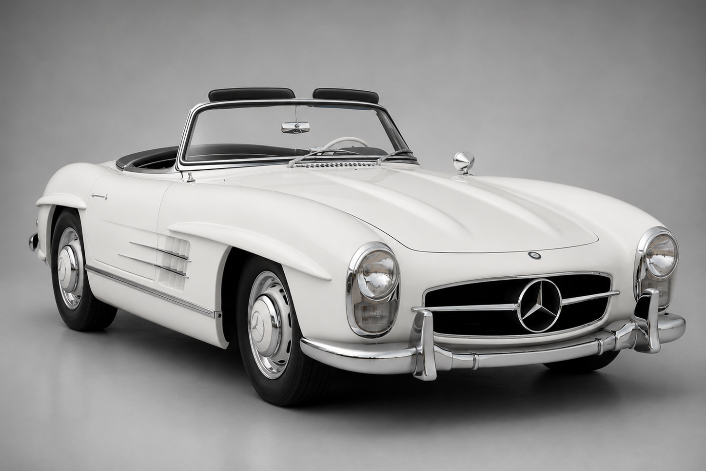 White Mercedes-Benz 300 SL Roadster with black soft top, chrome brightwork and wheel covers, photographed against a neutral grey studio backdrop.