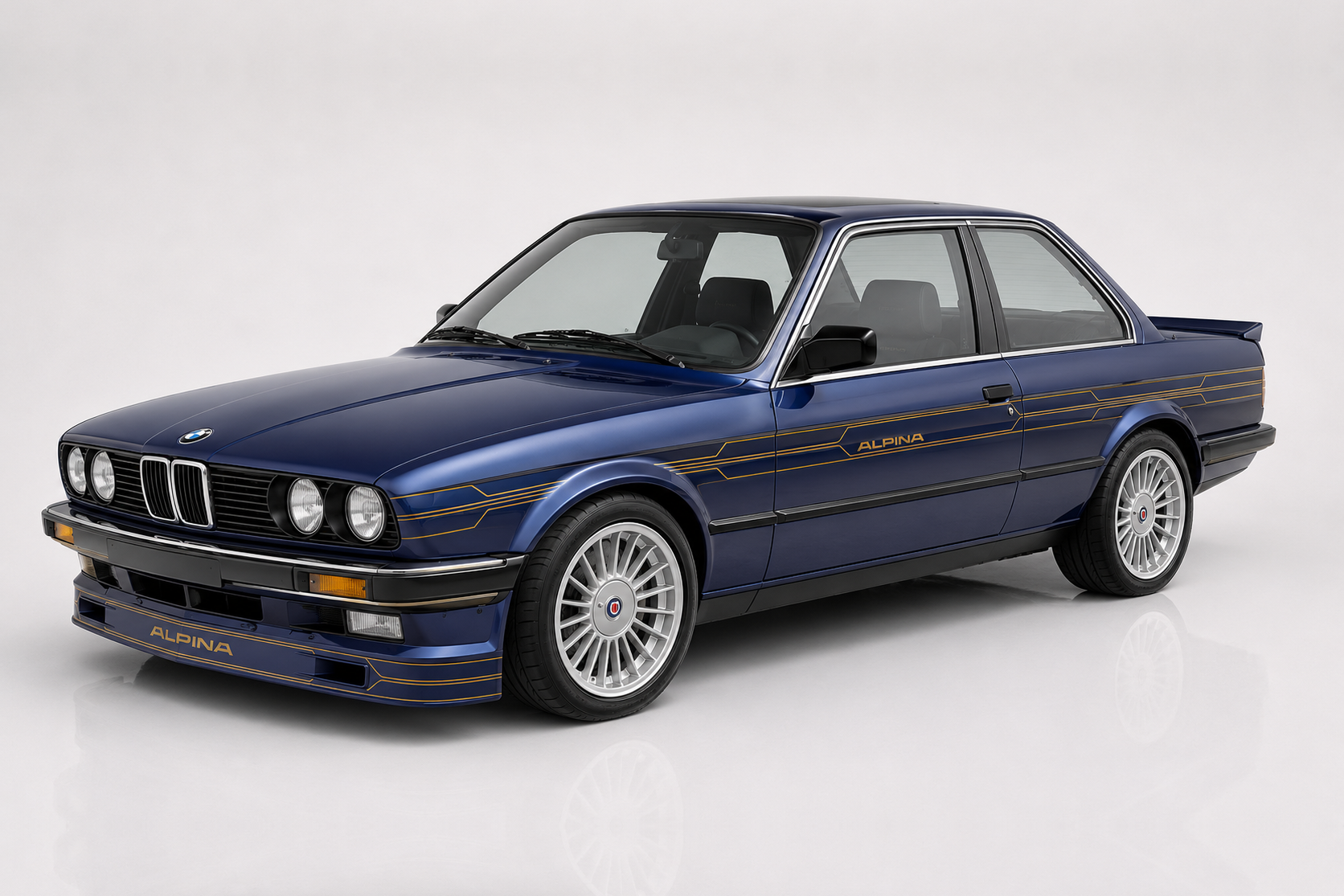 Dark blue Alpina B6 (E30) coupé in a studio setting, front three-quarter view showing the period Alpina blue/gold decoration stripes down the flanks, deep front spoiler with 'ALPINA' script, four-headlight BMW 3 Series shark-nose face and signature Alpina 20-spoke wheels — the six-cylinder Alpina M3 BMW never built.