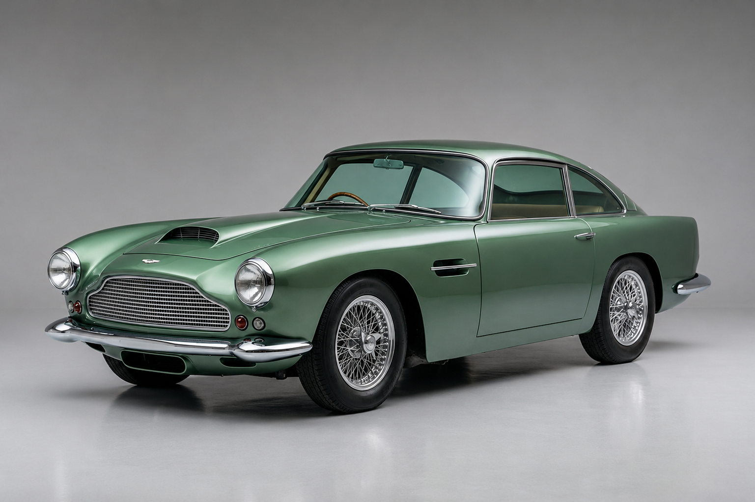 Metallic green Aston Martin DB4 photographed front three-quarter in a studio setting, showing the Touring Superleggera bodywork, chrome wire wheels, distinctive grille, bonnet scoop and side vent.