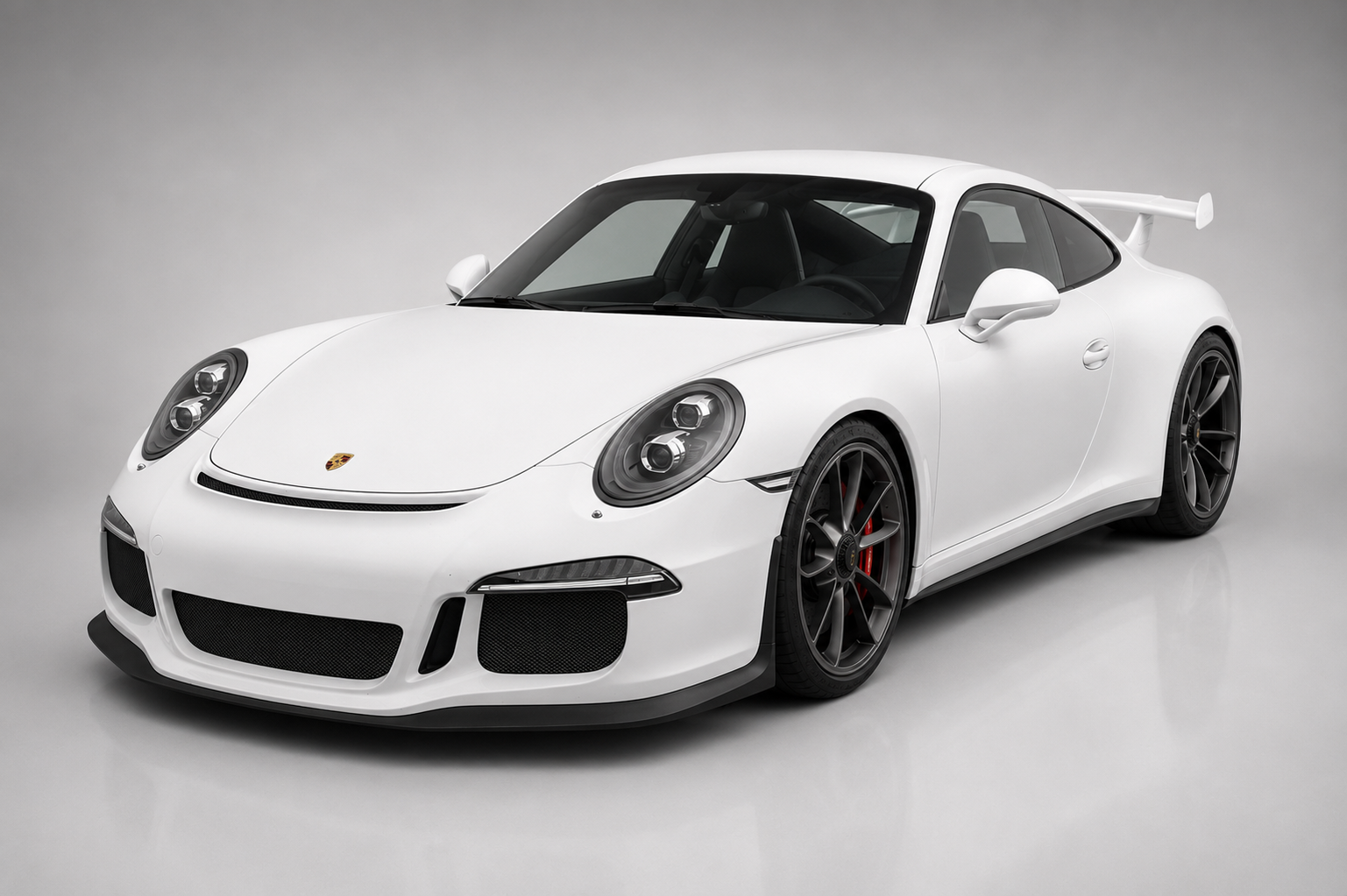 White Porsche 911 GT3 (991) in a grey studio, front three-quarter view showing the fixed rear wing, GT3 aero front end and gloss-black centre-lock alloy wheels.