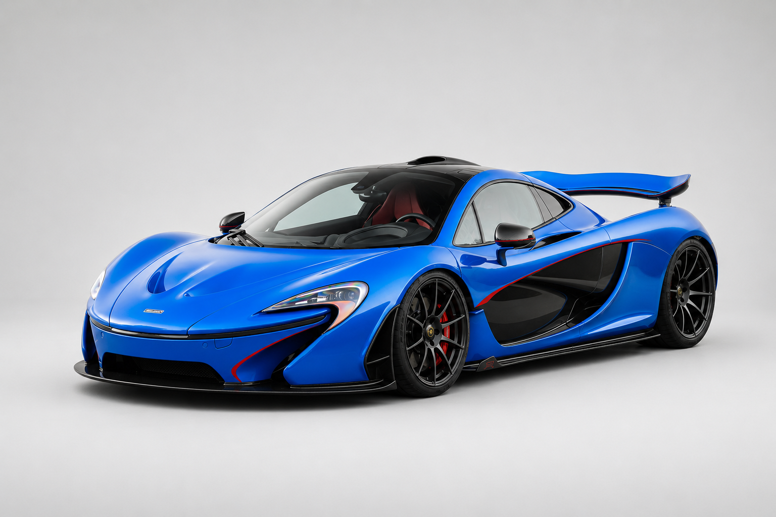 Blue McLaren P1 with red MSO accents in a light grey studio, front three-quarter view, active rear wing raised