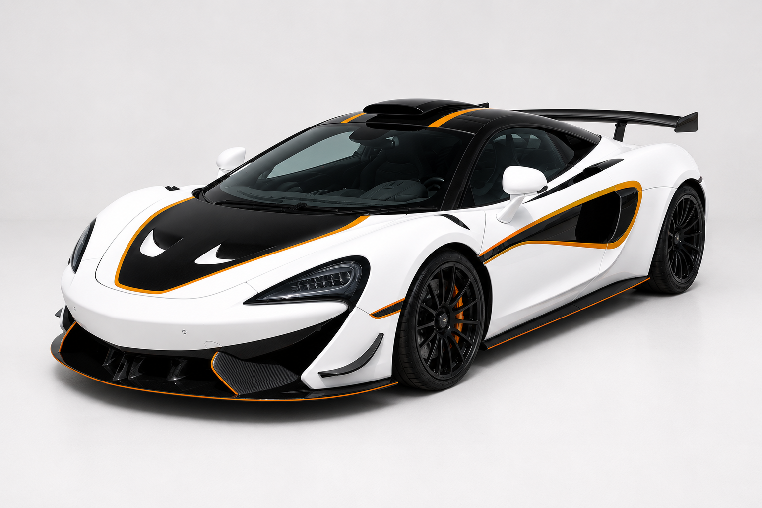 White McLaren 620R with black hood and roof and orange pinstripe accents in a studio setting, front three-quarter view showing carbon front splitter, side intakes and fixed rear wing.