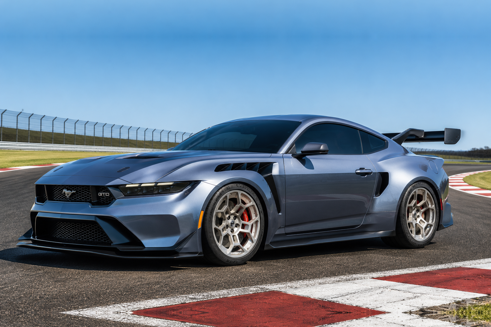 Seventh-generation Ford Mustang GTD in silver-blue on a race track, front three-quarter view showing the widened bodywork with front splitter, bonnet and front-wing vents, forged multi-spoke alloy wheels and a large swan-neck rear wing.