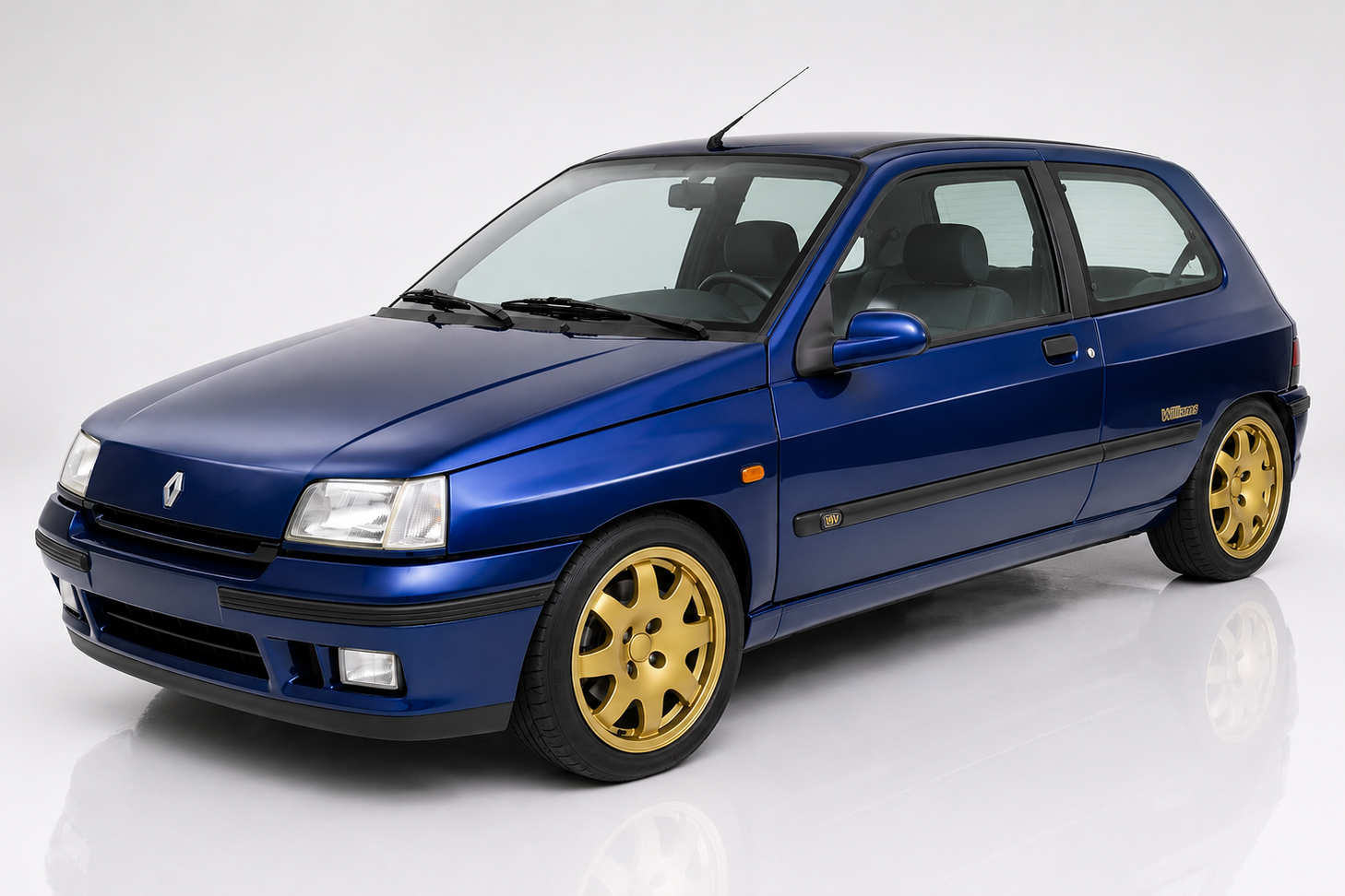 Sports Blue Renault Clio Williams three-door hatchback in a studio setting, front three-quarter view showing the widened front arches, Williams side decals and gold Speedline multi-spoke alloy wheels.