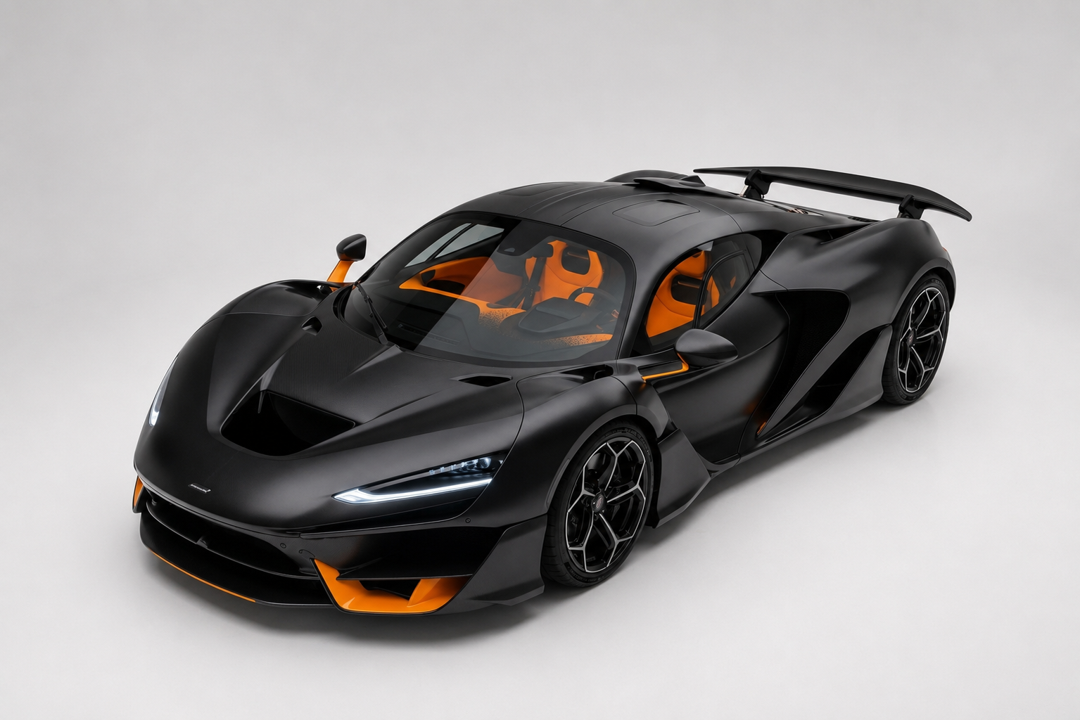 Matte black McLaren W1 with orange interior and lower-front accents, high fixed rear wing and body-colour wheels, front three-quarter view in a plain grey studio setting.
