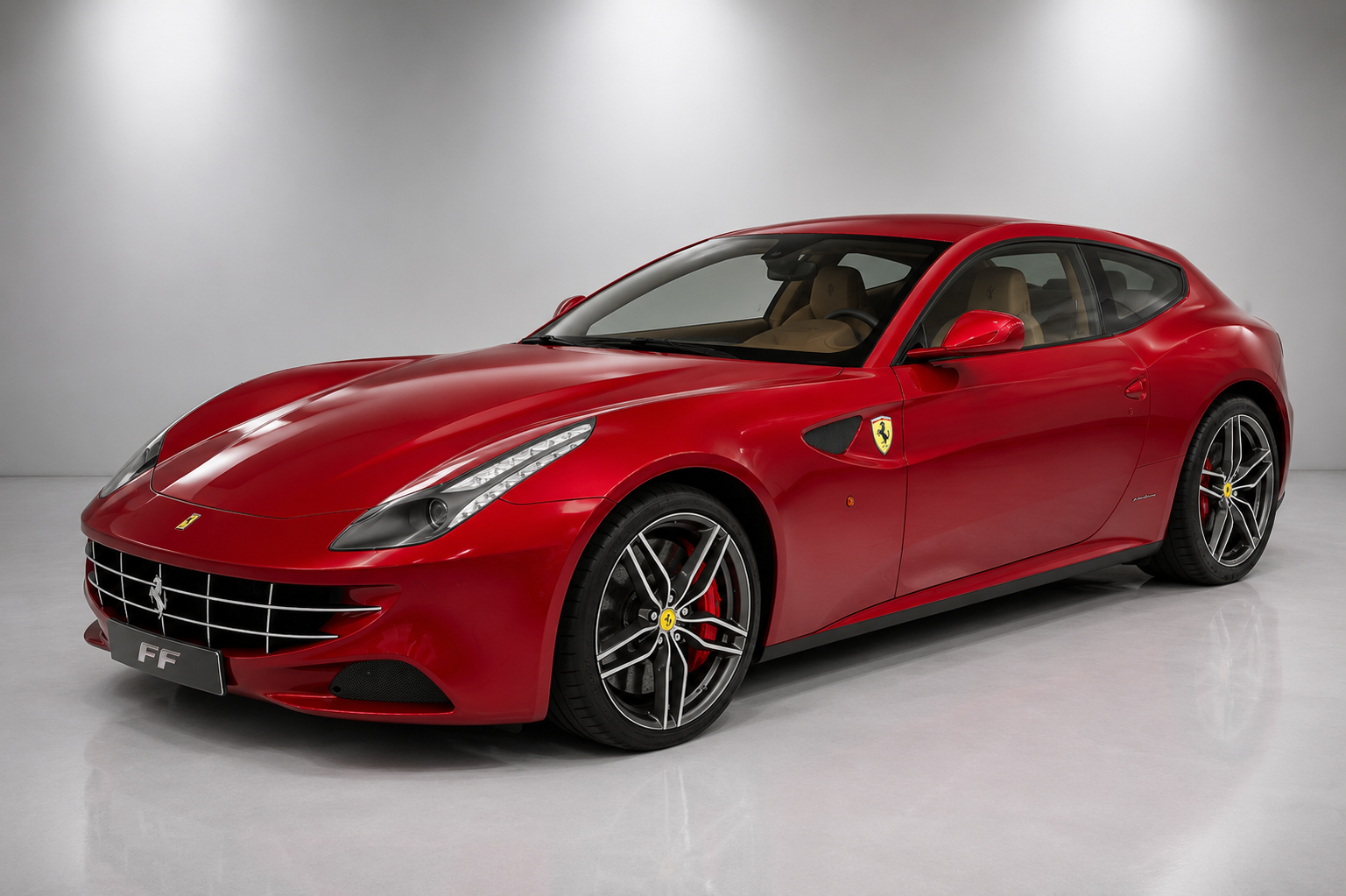 Red Ferrari FF shooting brake in a studio setting, showing the Pininfarina-designed four-seat V12 bodywork, four-wheel-drive stance and five-spoke alloy wheels.