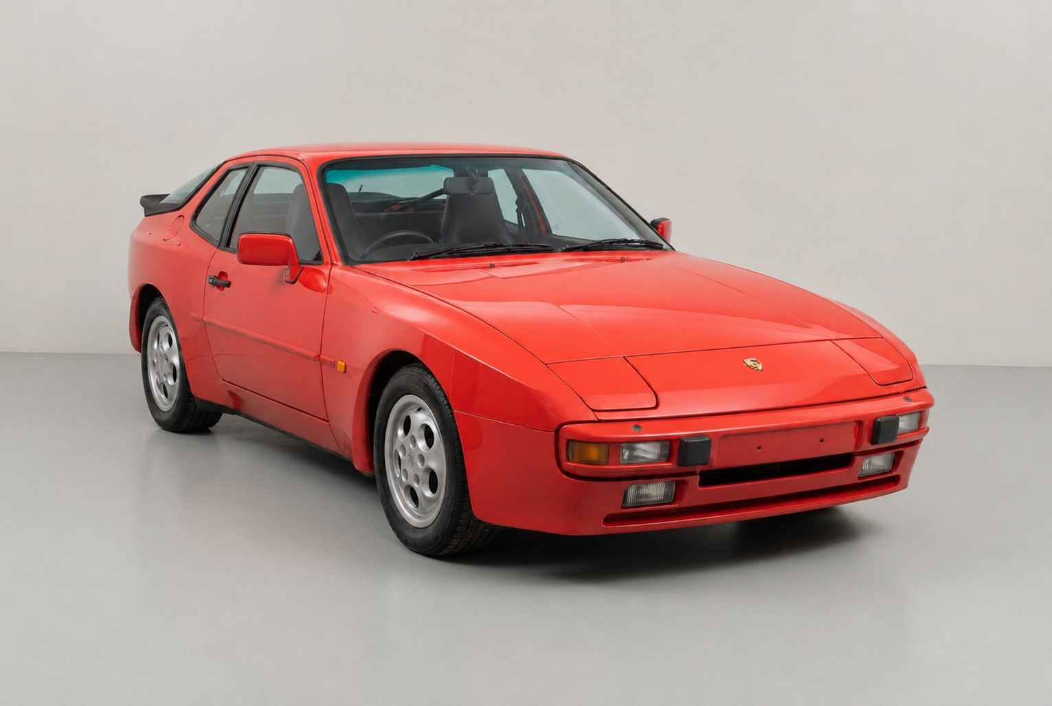 Guards Red Porsche 944 coupé with pop-up headlamps and phone-dial alloy wheels, front three-quarter studio view