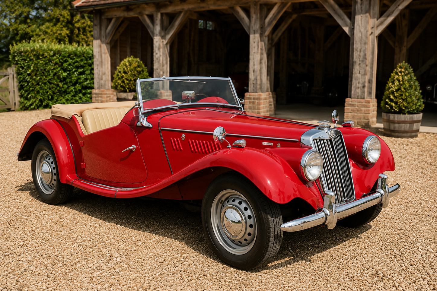 Red MG TF roadster with tan soft top and interior, front three-quarter view on a gravel courtyard outside a timber-framed estate building; sloping MG grille, faired-in headlights and chrome wire wheels.