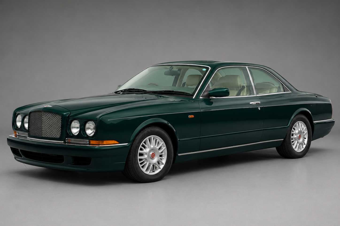 British racing green Bentley Continental R coupe photographed front three-quarter in a studio, showing the twin round headlamps flanking the mesh Bentley grille, chrome side trim and multi-spoke alloy wheels.