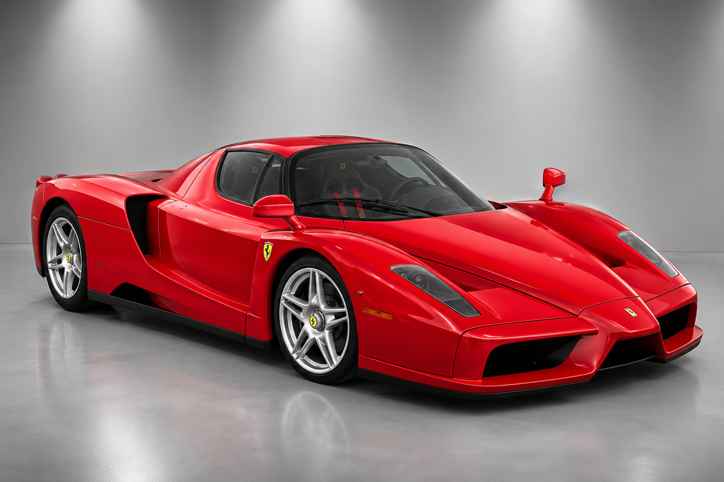 Red Ferrari Enzo hypercar in a studio setting, showing the low-slung Pininfarina bodywork, silver five-spoke wheels and rear spoiler.