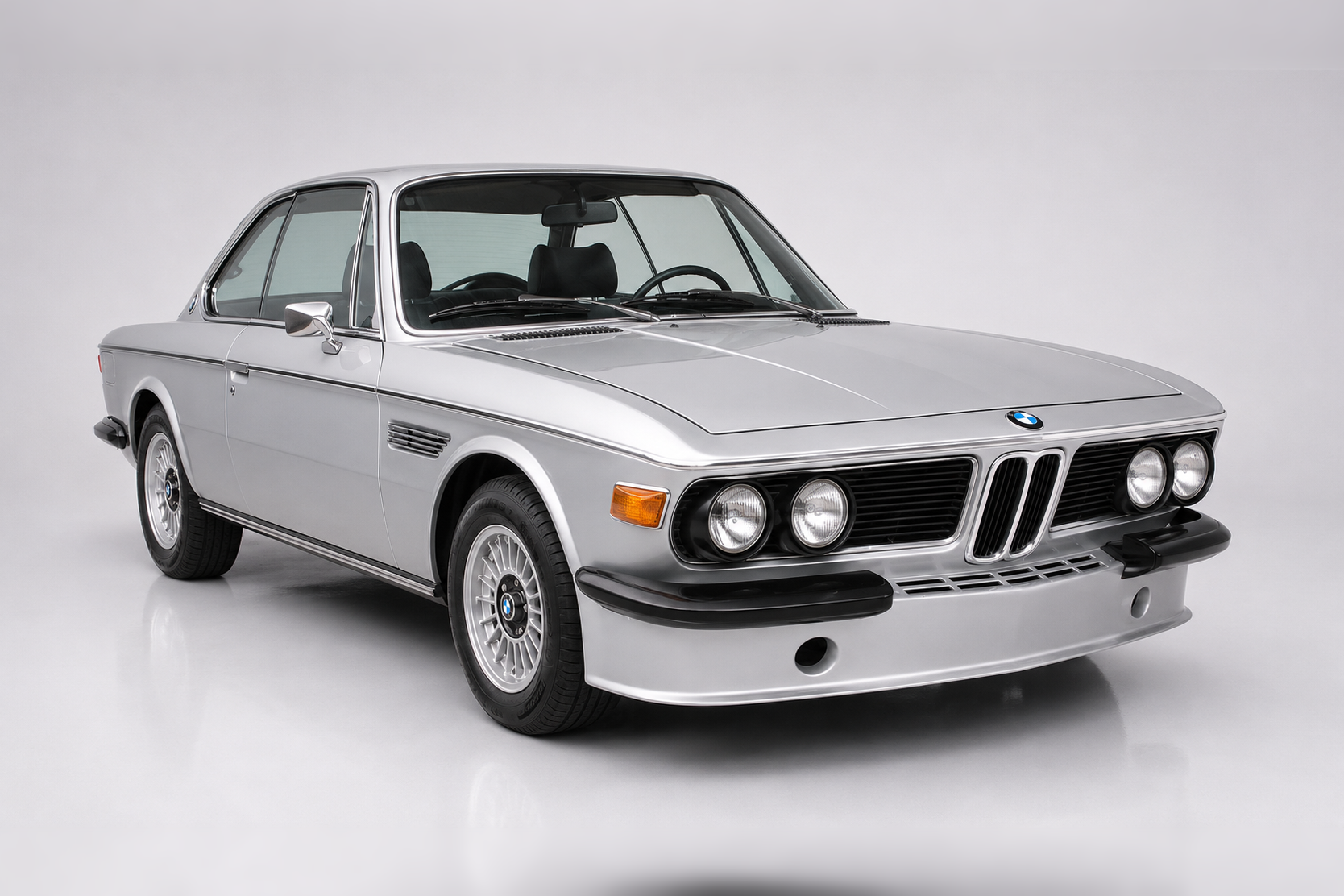 Silver BMW E9 3.0 CS coupé, front three-quarter studio view, showing the quad headlights, twin-kidney grille, pillarless side glass, Hofmeister kink and slim chrome bumpers.