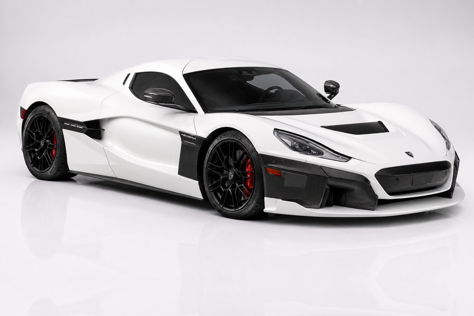 White Rimac Nevera electric hypercar in a studio setting, front three-quarter view showing the low mid-engine silhouette, carbon-fibre front splitter and side vents, black lightweight wheels with red brake calipers and body-colour bonnet with Nevera script.