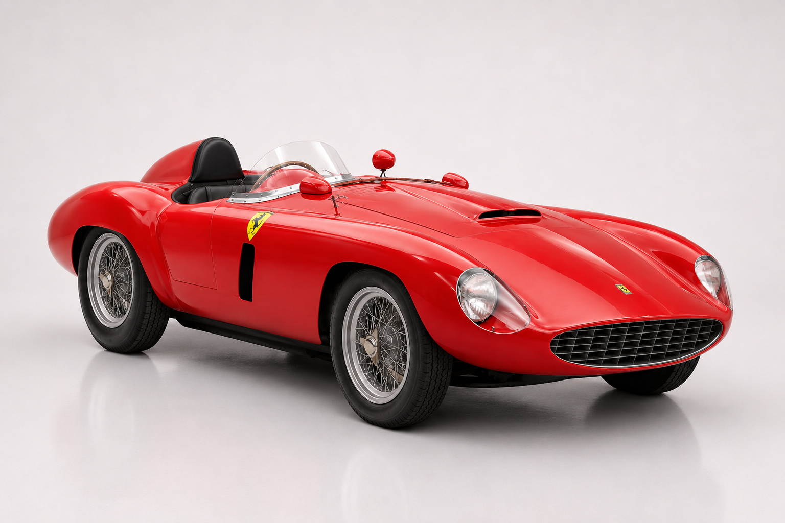 Red Ferrari 735 S barchetta photographed in a studio, front three-quarter view showing the oval grille, low racing windscreen, headrest fairing, faired-in headlamps and centre-lock wire wheels.