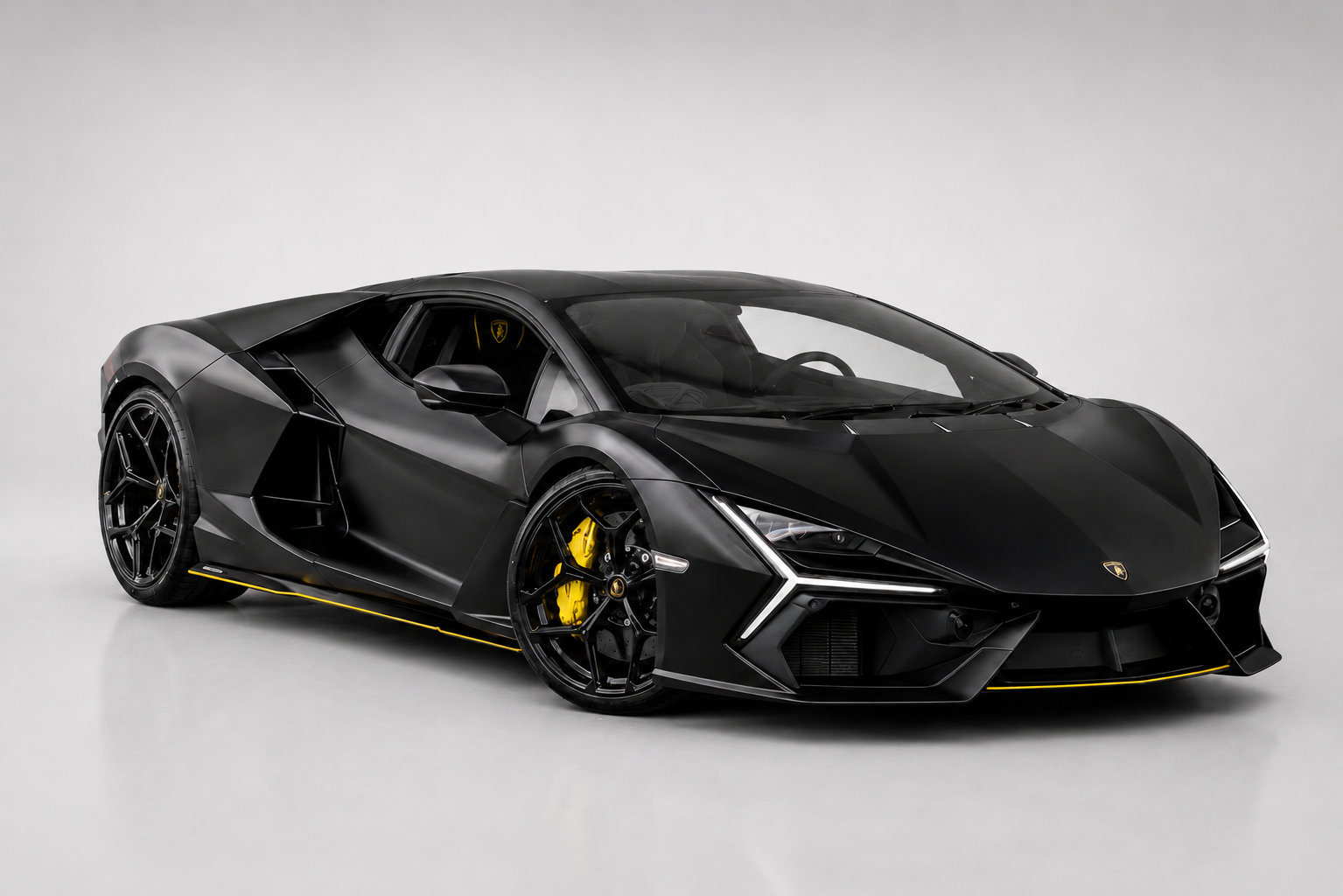 Matte black Lamborghini Revuelto coupe in a studio setting, front three-quarter view showing the angular carbon-fibre bodywork with yellow accent stripe along the sill, Y-shaped LED headlights, black multi-spoke wheels and yellow brake calipers.