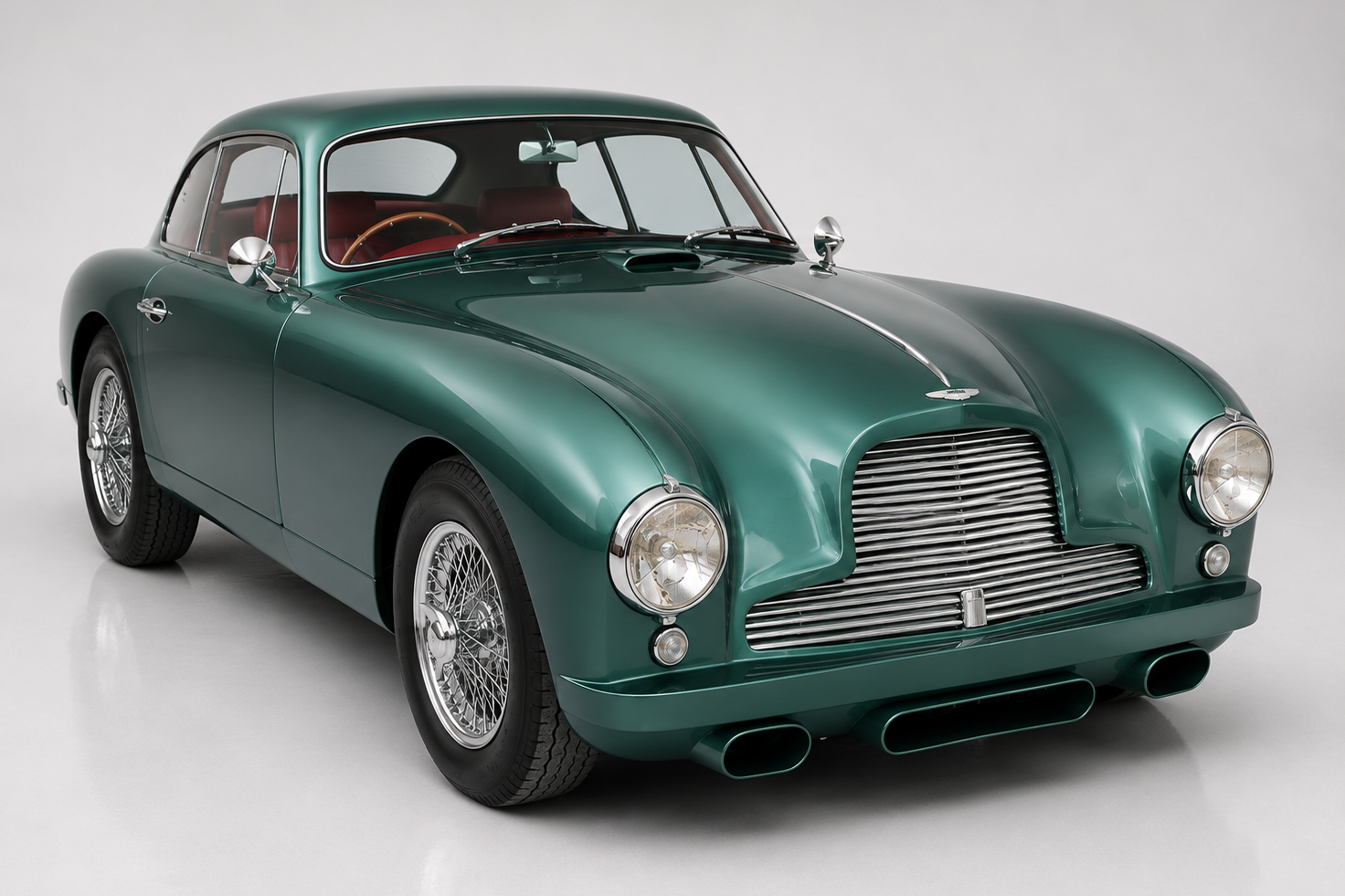 Dark green Aston Martin DB2 fixed-head coupe in a bright studio, front three-quarter view showing Frank Feeley's low bonnet with horizontally slatted chrome grille, round headlamps, chrome wire wheels and a red leather interior — Aston's first true postwar grand tourer.