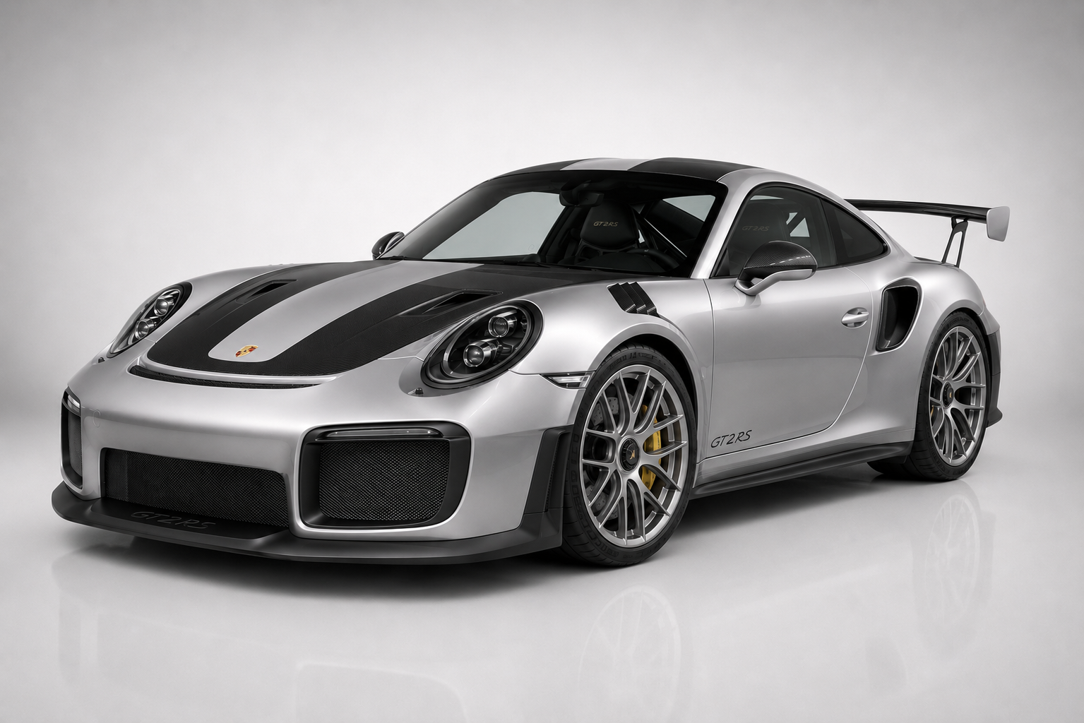 GT Silver Porsche 911 GT2 RS (991) with exposed carbon roof and hood in a studio, front three-quarter view showing GT2 RS decals, carbon aero and multi-spoke forged wheels.