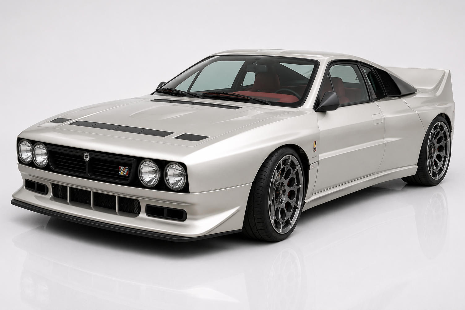 Silver Kimera Evo37 in a studio setting, front three-quarter view showing the Lancia 037-inspired silhouette with quad round headlamps, deep front splitter, factory bonnet vents, integrated side sills and multi-spoke Speedline-style wheels — the RWD restomod tribute to Lancia's last RWD WRC champion.