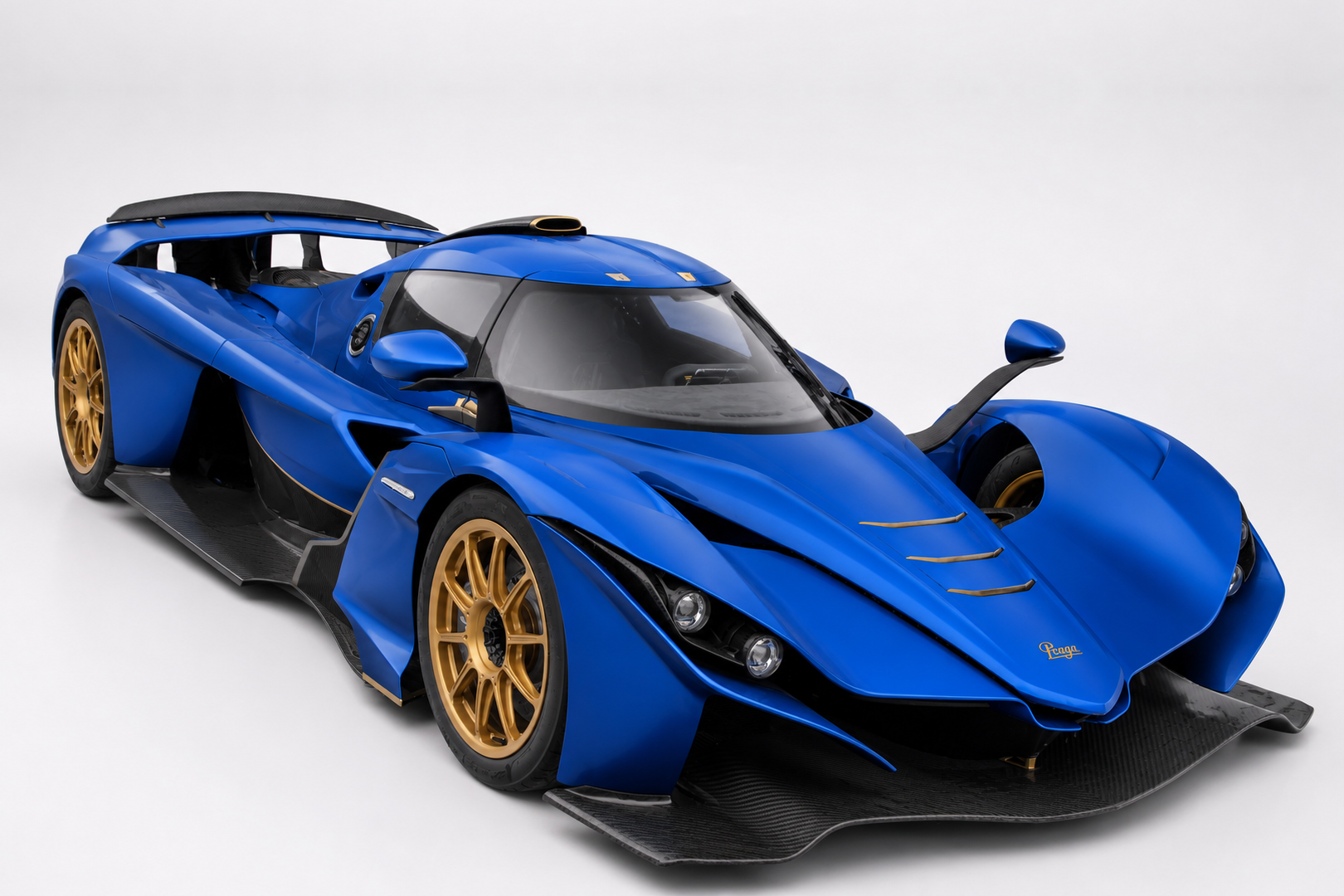 Blue Praga Bohema road-legal track hypercar in a studio setting, front three-quarter view showing the low prototype-style carbon bodywork, aggressive splitter and vents, gold multi-spoke centre-lock wheels and Praga script on the front fender.