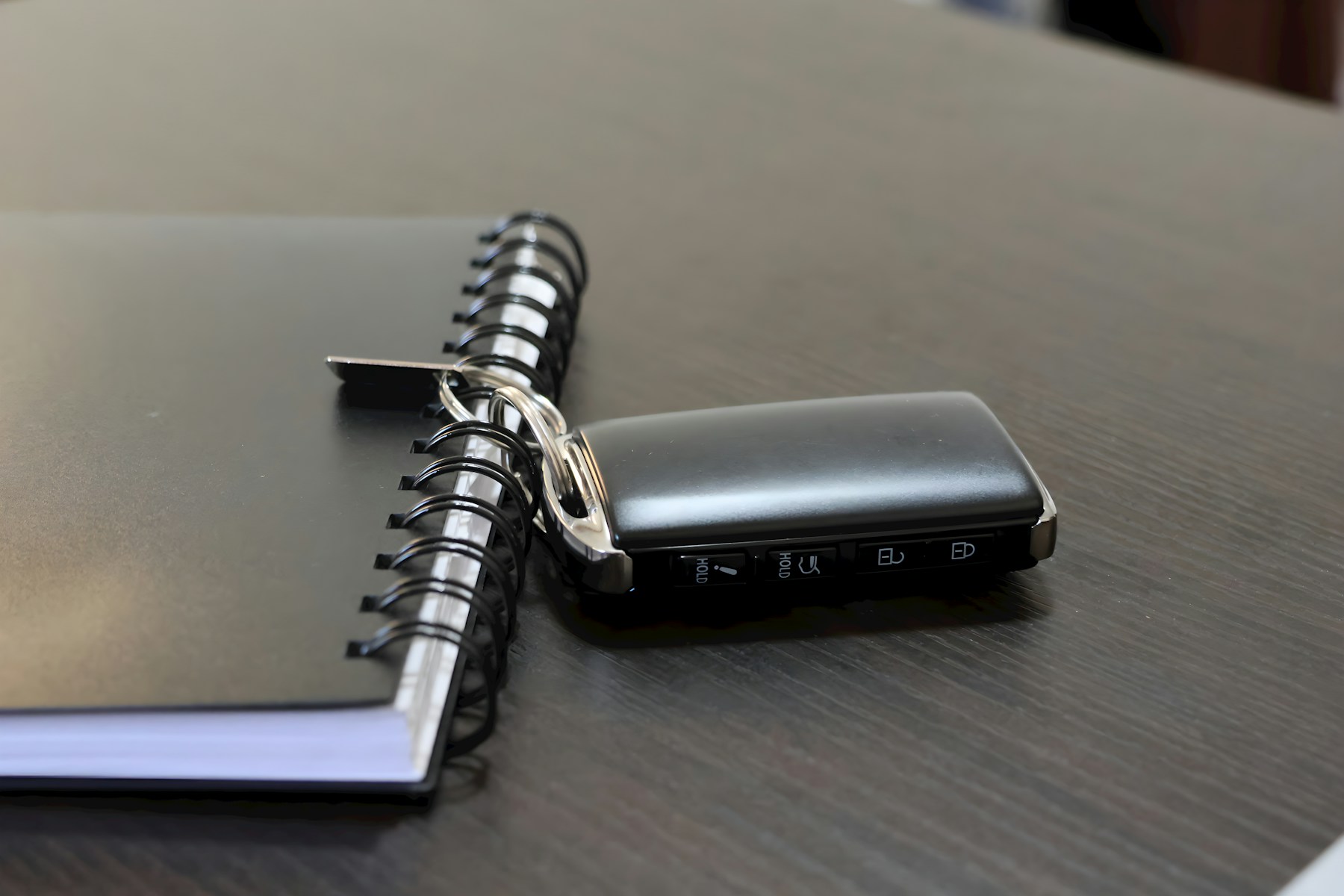 An open vintage car logbook on a walnut desk with brass keys.